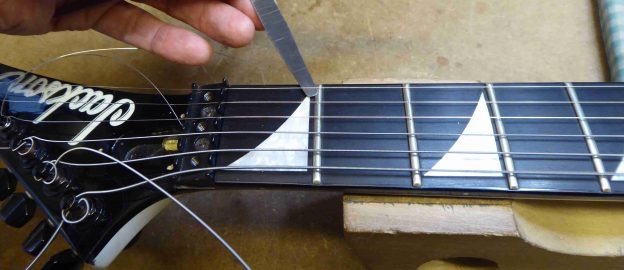 Using a feeler gauge to check the action height at the first fret on a Jackson Guitar