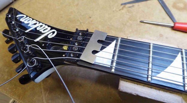 A shim which will be placed under the locking nut of a Jackson guitar in order to raise the action at the first fret.