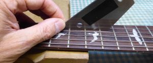 A fret-rocker, a calibrated straight edge placed over 3 frets. If the fret tops are even then it will not move or "rattle"