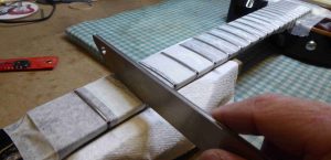 Rounding off the fret tops with a fret crowning file.