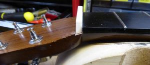 A bone nut blank fitted into the slot on a Martin acoustic. the bottom now angled to fir properly