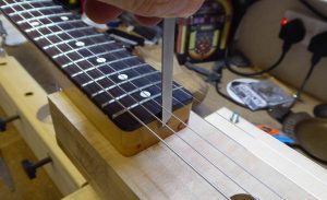 The truss-rod screw at the heel of a Fender Telecaster neck. Mounted on a neck jig, with strigs fitted.