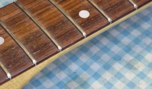 A close-up view of the fret ends on a 1980s Tokai "Stratocaster". The fret ends are protruding from the neck and are a little sharp.