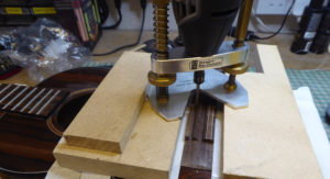 Deepening the bridge slot with a router in order to accommodate the electric pickup.