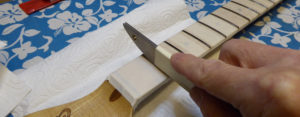 Using a rounded fret crowning file to round off the fret-tops again.