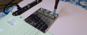 Adjusting the saddle height screw on the Bass E string