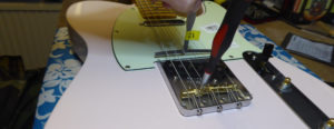 Adjusting the saddle height screw on the other strings