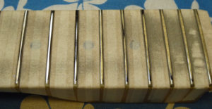 You can see here where the levelling beam has ground the frets and the low spots that haven't been reached yet.