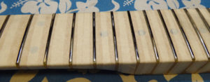 You can see here where the levelling beam has ground the frets and the low spots that haven't been reached yet.